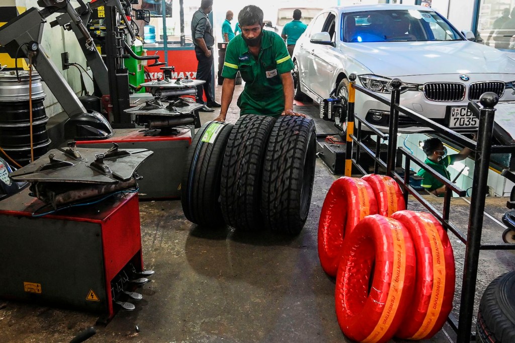 A technician swapping car tires: buying cost-effective summer tires can help you save money on winter tires and separate summer tires in the long run. In this picture taken on January 29, 2021, workers check tyres at a repair shop in Colombo. - With no foreign cash coming in as Covid-19 cripples the tourism industry, the government in March imposed a ban on many imports to stop money leaving the country, so that it can pay 4.5 billion USD this year to service its international debt. Prime Minister Mahinda Rajapaksa's ban on "non-essential" items has also seen a surge in prices for other goods, including car tyres, floor tiles and even toilets. (Photo by LAKRUWAN WANNIARACHCHI / AFP) / TO GO WITH 'SRI LANKA-HEALTH-VIRUS-TRADE-ECONOMY,FOCUS' BY AMAL JAYASINGHE (Photo by LAKRUWAN WANNIARACHCHI/AFP via Getty Images)