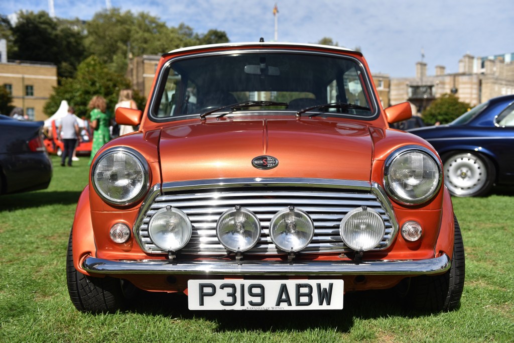 A classic orange Mini Cooper at a concourse event