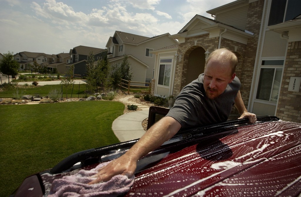 Man Washes His SUV in the driveway at home