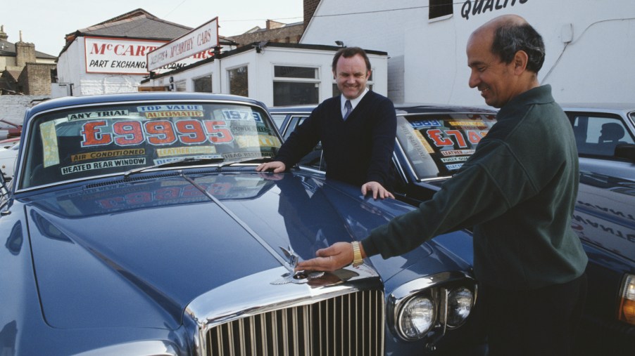 Second hand car salesman Vincent McCann admires a 1979 Bentley with a customer, UK, 1992. (Photo by Tom Stoddart Archive/Getty Images) Do open recalls change a cars trade-in value?