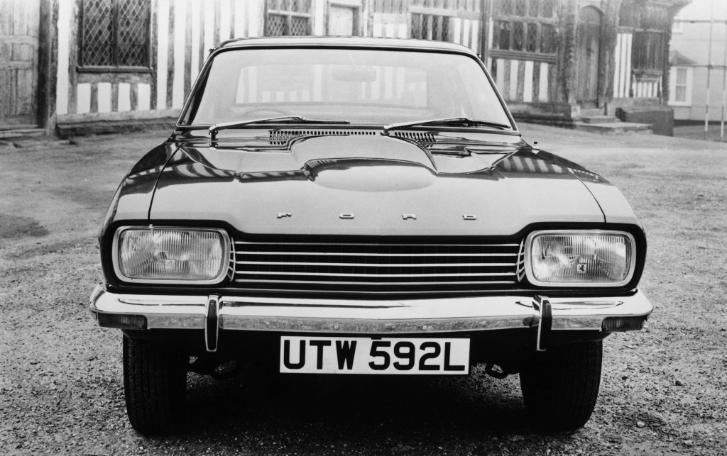 The front end of an old 1973 Ford Capri sedan in black and white