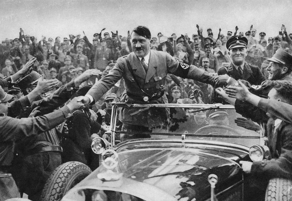 Adolf Hitler rides in a Mercedes-Benz convertible while greeting supporters in Nuremberg 1933