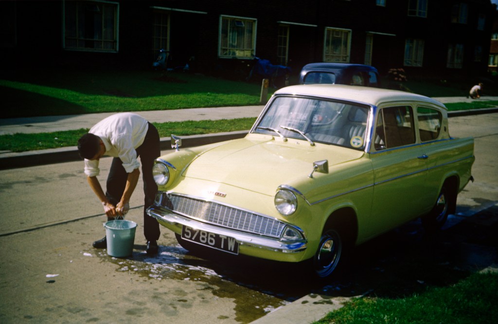Man Washes His Classic Ford Anglia Car