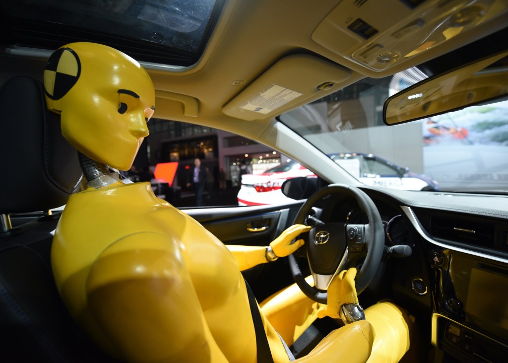 A crash test dummy at the wheel of a Toyota Corolla