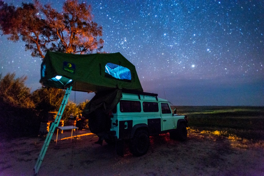 Botswana, Africa- Land Rover parked with a pop up tent on its roof under the night sky. (Photo by: Edwin Remsburg/VW Pics via Getty Images) One of the 5 Best Rooftop Tents For Overlanding -- According to Popular Mechanics