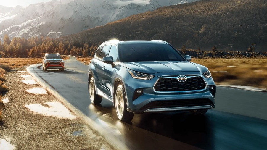 A blue 2021 Toyota Highlander driving with mountains in the background.