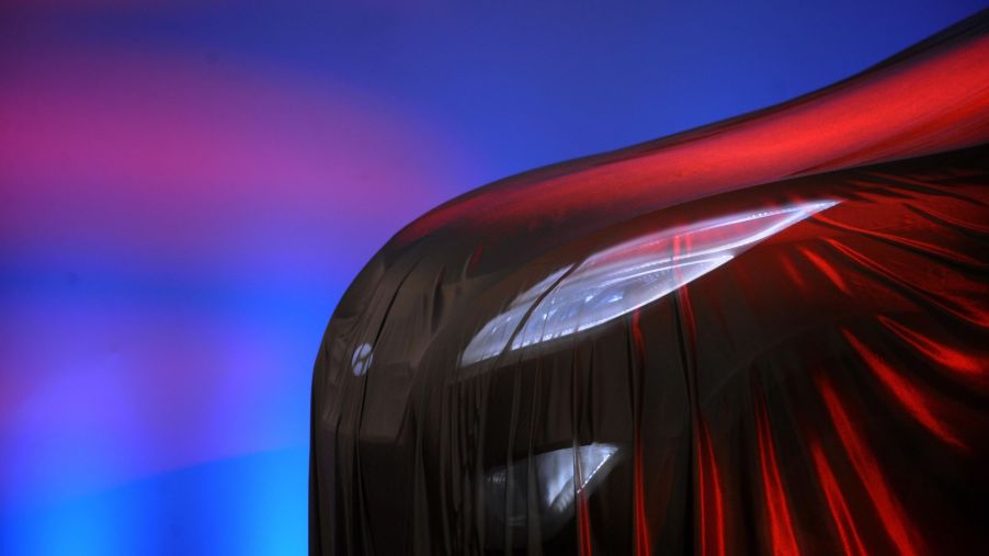 A headlight covered in a veil that gives off a red glow with a blue and pink background.