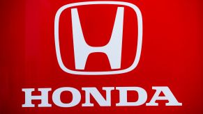 A white Honda logo with Honda written underneath on a red background.