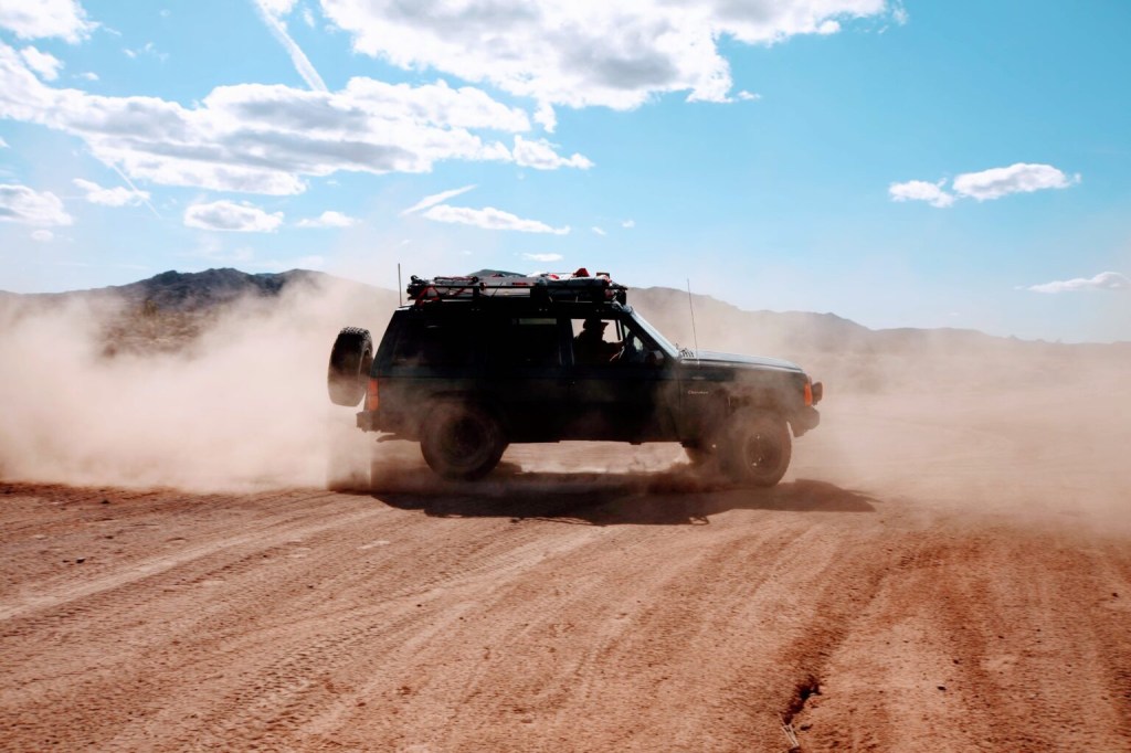 Classic 90s off-roader, Jeep Cherokee kicking up dust in the desert