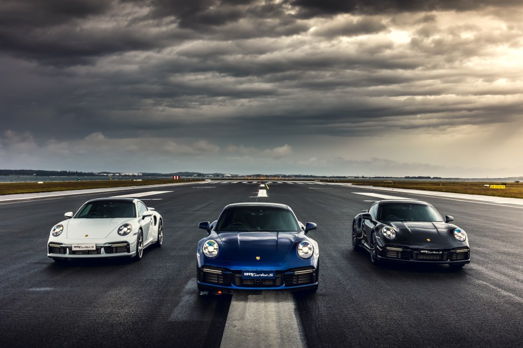 A lineup of three Porsche 911 Turbo models on a runway