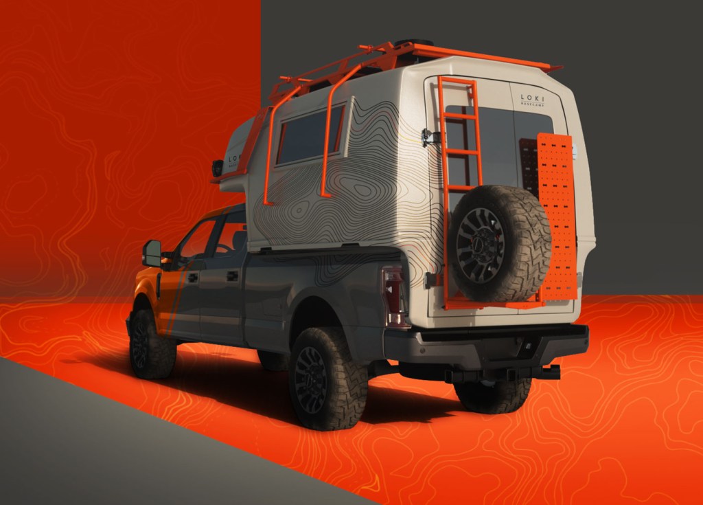 The rear of the Icarus camper, with a tire mounted on the back and orange railing covering the exterior