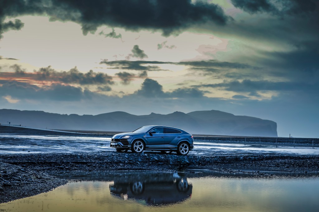 Blue Lamborghini Urus parked in front of scenic backdrop