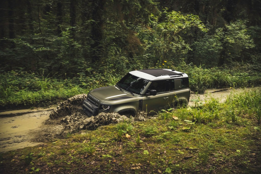 Profile shot of a 2021 Land Rover Defender 90 review as it chrages through some muddy water