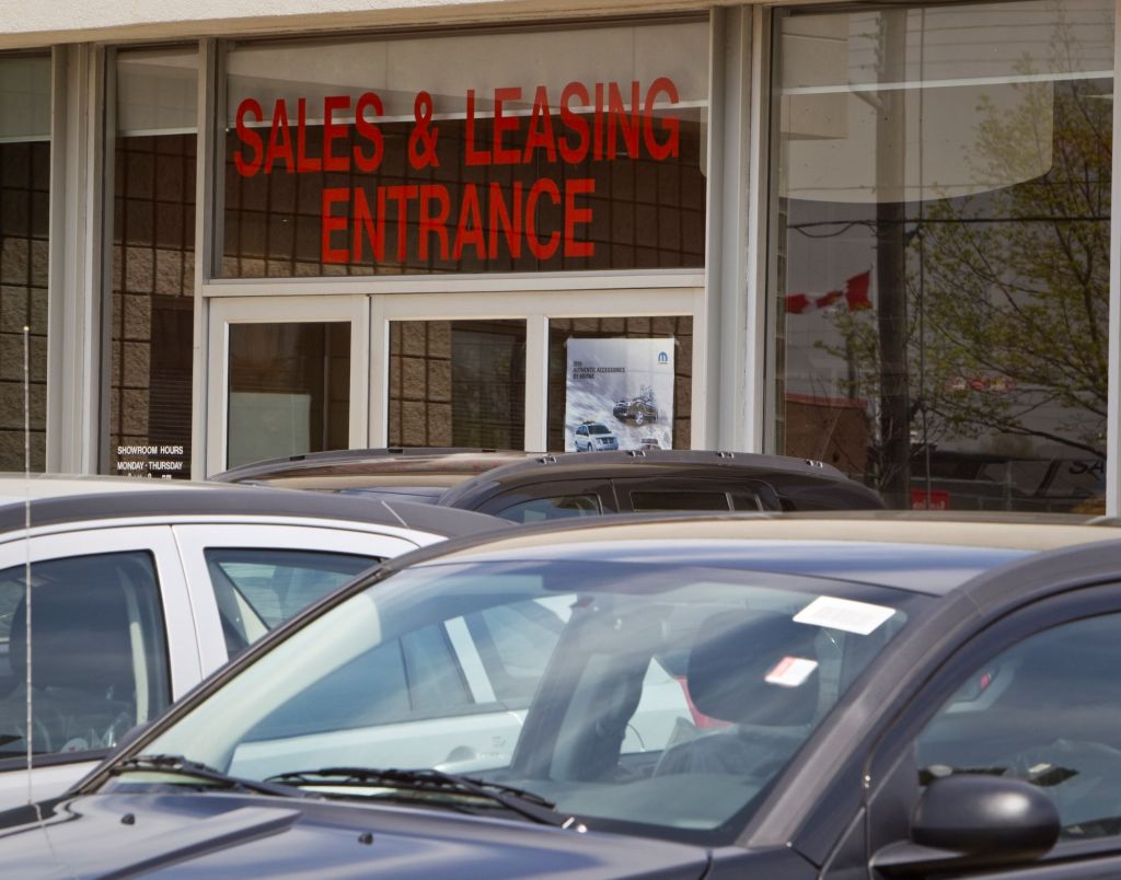 Sales and Leasing Entrance is written above a door with cars sitting in front of it.