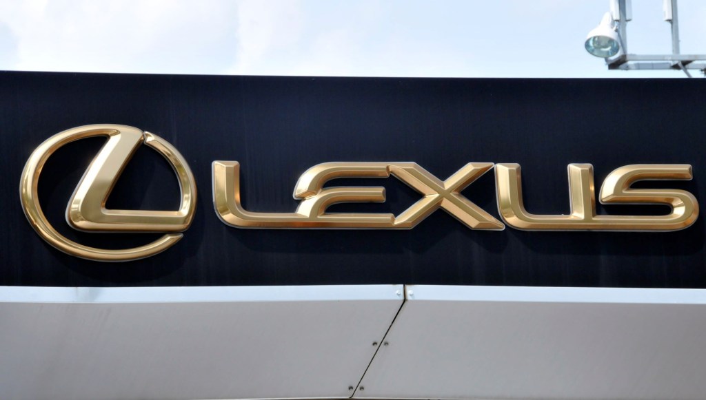 A black sign with Lexus and the company's logo in gold on it.