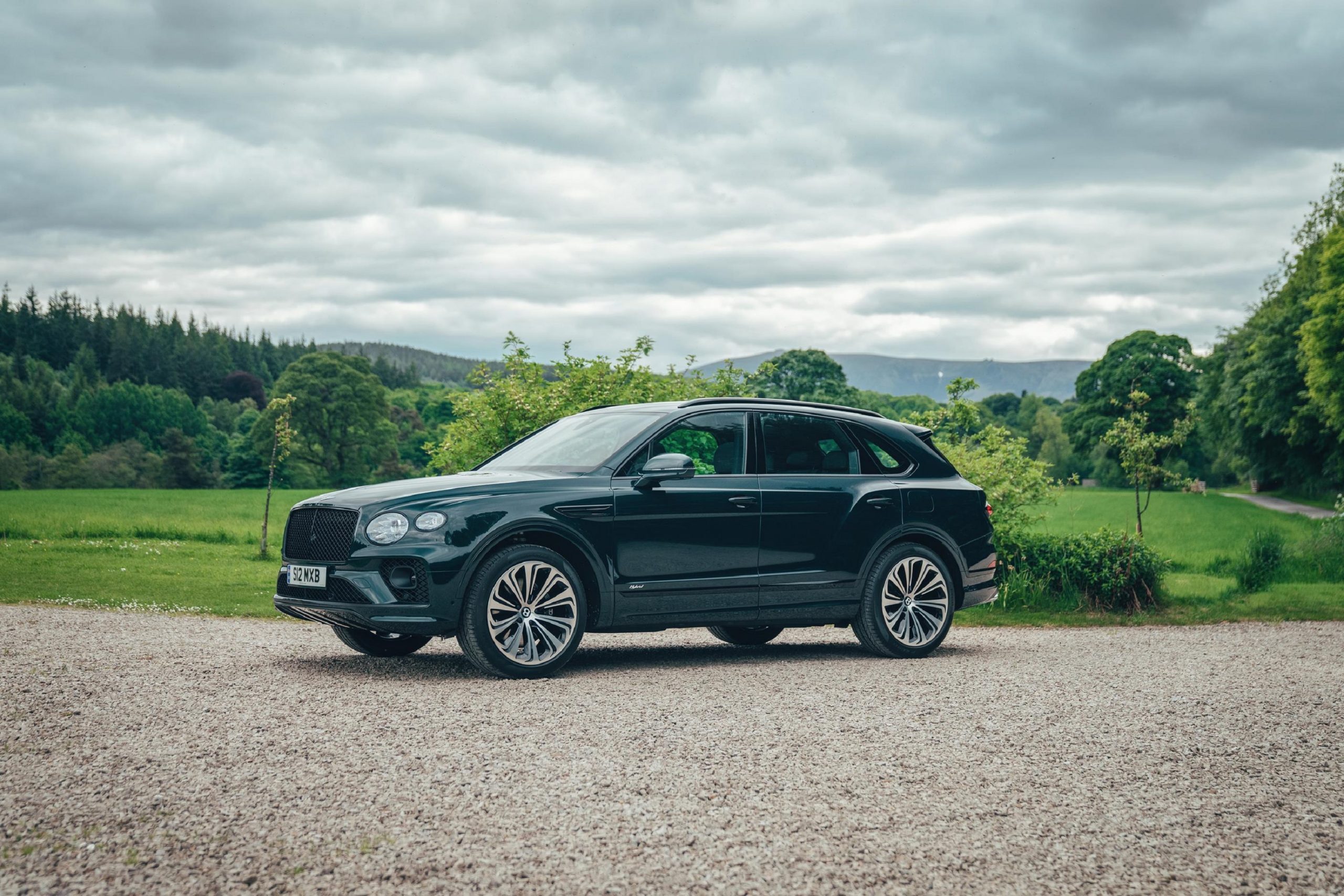 A forest green 2021 Bentley Bentayga Hybrid in the forest