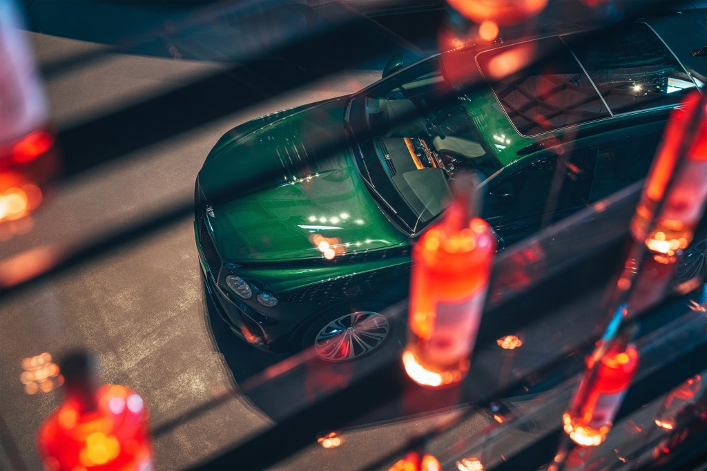 A green Bentayga Hybrid photographed through lights at night