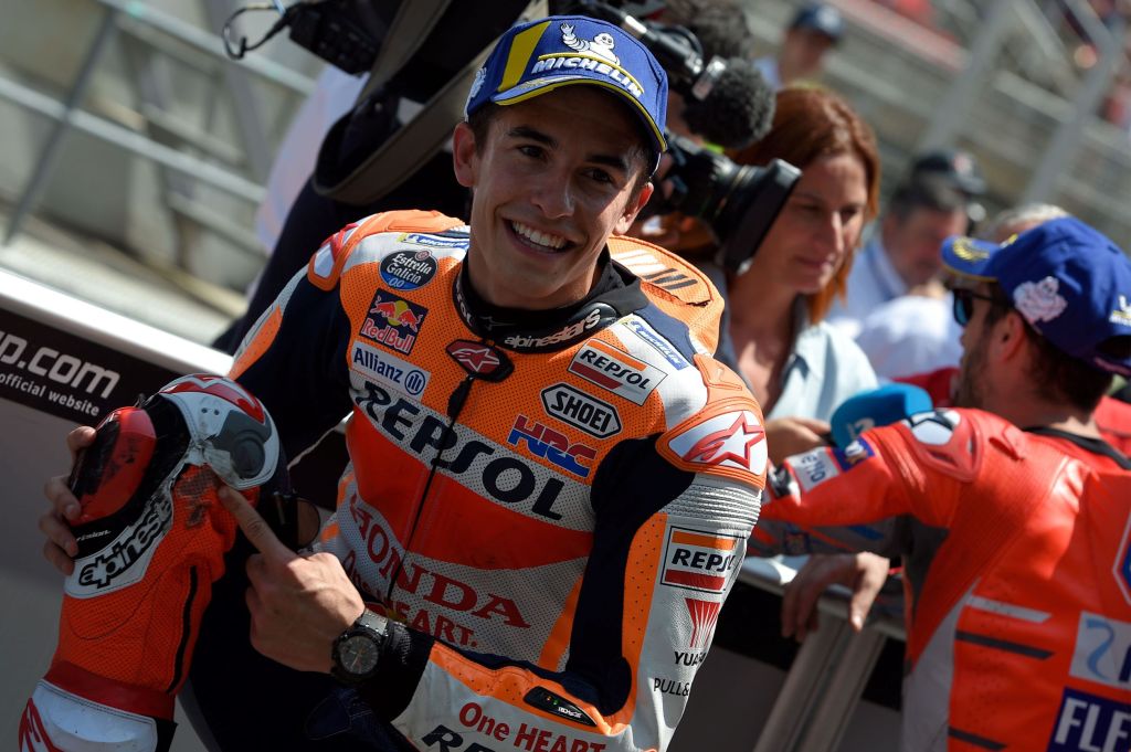 MotoGP racer Marc Marquez points out the damage on his orange Repsol Honda leather motorcycle race suit at the 2018 Catalunya Grand Prix