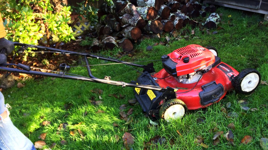 A person mowing the lawn in fall, while also mulching leaves with a lawn mower