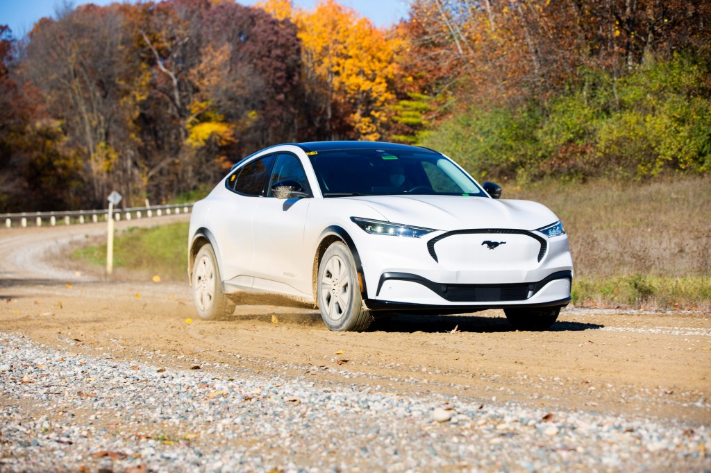 A white Ford Mustang Mach E drives down a gravel road during durability tests