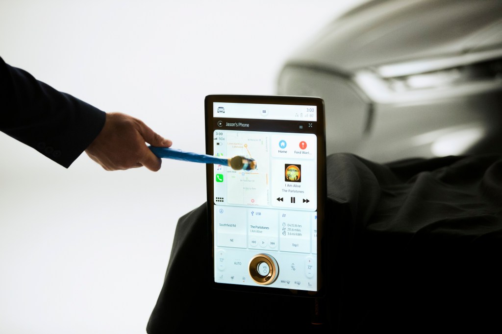 A man takes a hammer to the touchscreen on the Mach E