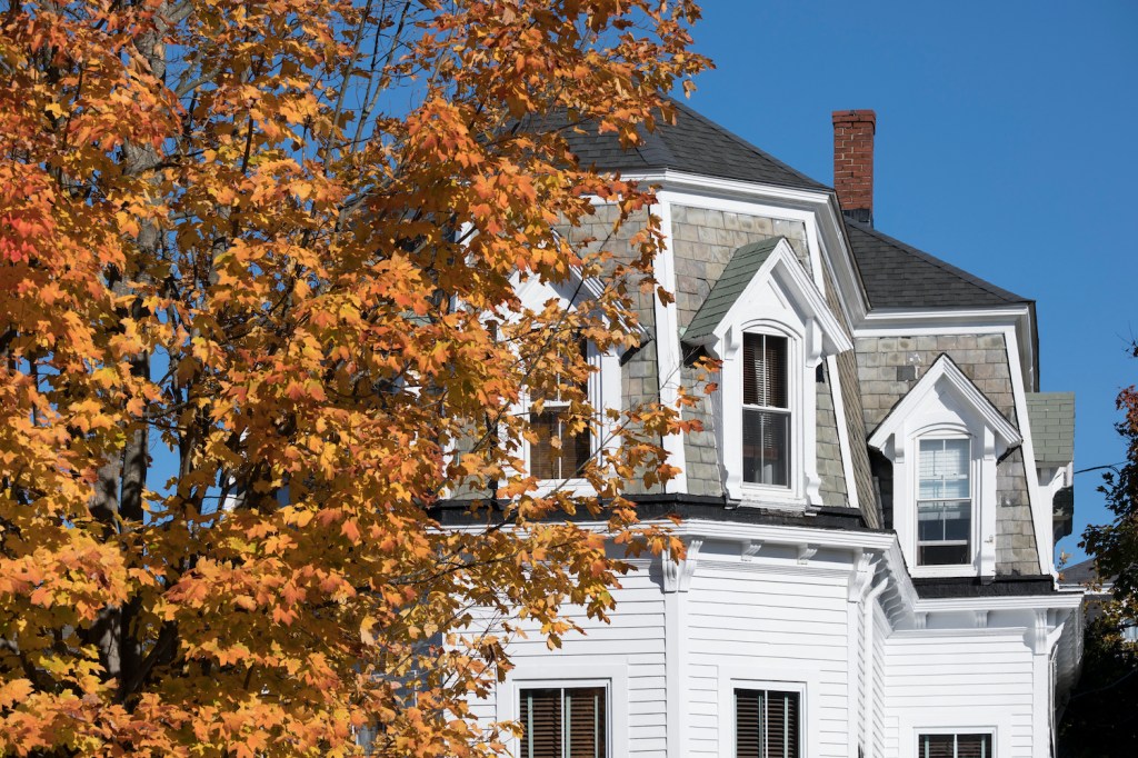 A Clapboard Home in Newport, Rhode Island, USA with fall leaves in front of it