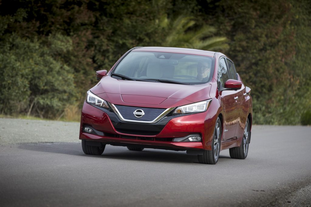 The front end of a red 2018 Leaf on a forested backroad