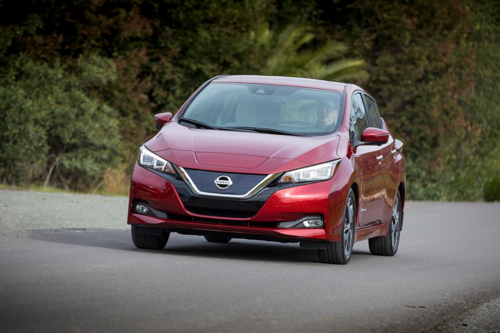 The front end of a red 2018 Leaf on a forested backroad