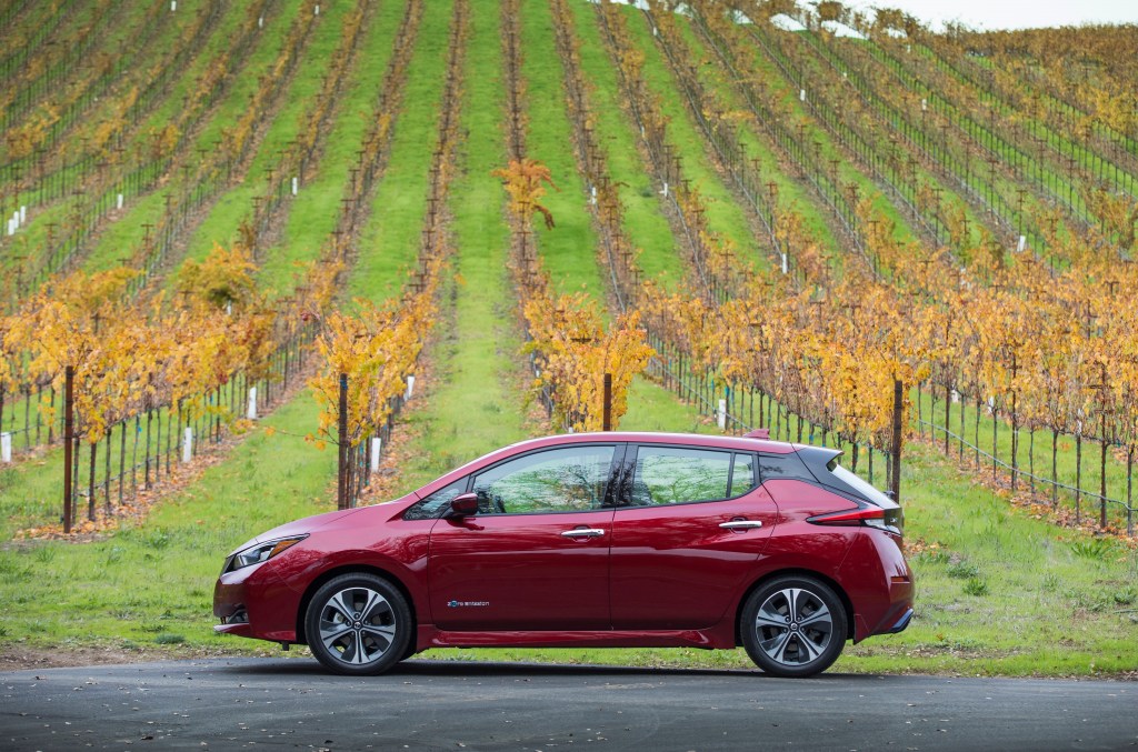 A red Nissan Leaf photographed in profile in a field