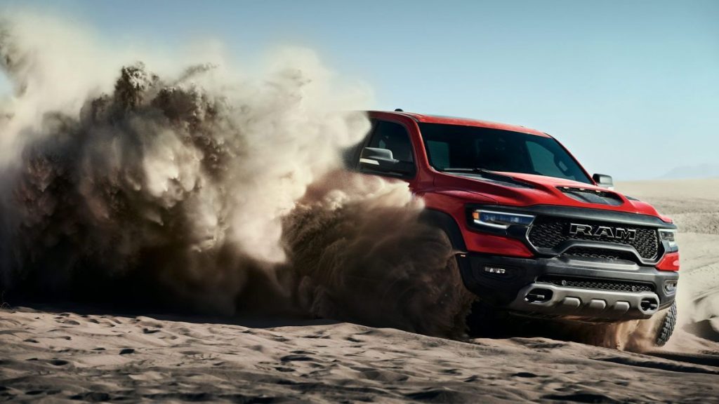 This is a publicity photo of a red RAM TRX throwing up dust. Read about the Rise of The Supertruck: Brabus, Tesla, and Hummer Lead This New Exotic Truck Class