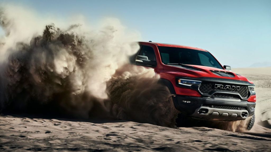 This is a publicity photo of a red RAM TRX throwing up dust. Read about the Rise of The Supertruck: Brabus, Tesla, and Hummer Lead This New Exotic Truck Class