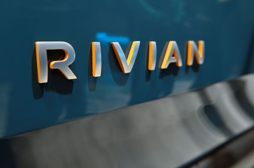Rivian spelled out in metal letters on the back of a dark teal piece of metal.