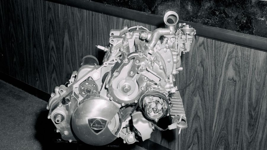 A black and white picture of a rotary engine with a wooden backdrop.