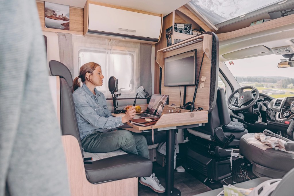 Woman sits at the fold-out work station on the ultimate work remote camper rig