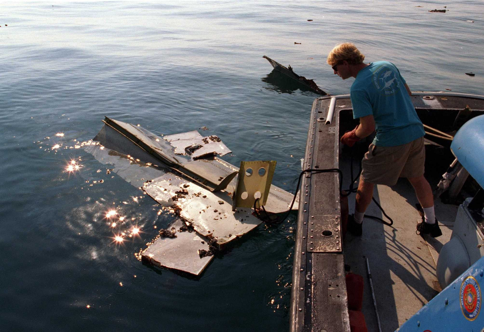 In the aftermath of the crash of TWA Flight 800, crew members of the Coast Guard cutter Jupiter load pieces of the jetliner on to the ship's deck on July 18, 1996. A section of the plane's tail can be seen in the water.