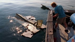 In the aftermath of the crash of TWA Flight 800, crew members of the Coast Guard cutter Jupiter load pieces of the jetliner on to the ship's deck on July 18, 1996. A section of the plane's tail can be seen in the water.