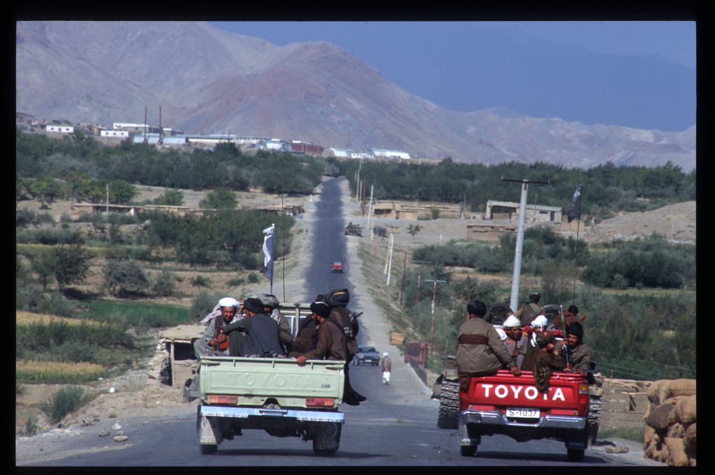 Taliban forces riding down the road in Toyota pickup trucks