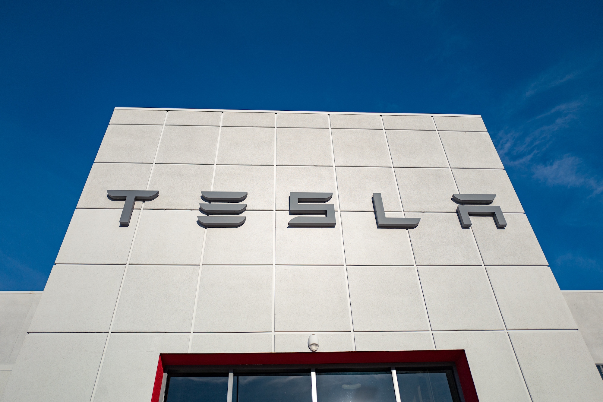 Low-angle view of the façade of a Tesla Motors dealership with logo and sign in Pleasanton, California, on July 23, 2018