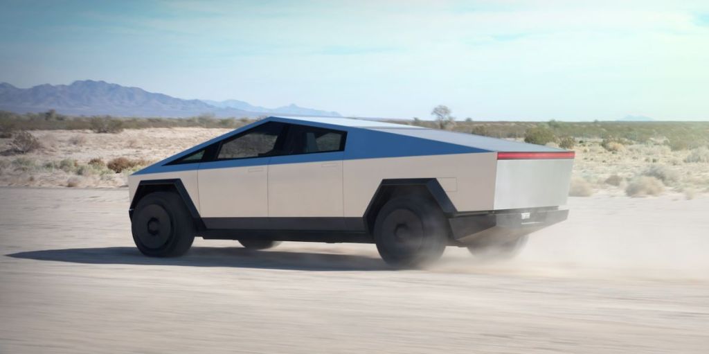 This is a publicity photo of a silver Tesla Cybertruck driving through the desert. Read about the Rise of The Supertruck: Brabus, Tesla, and Hummer Lead This New Exotic Truck Class