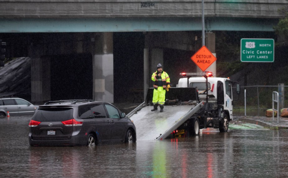 A tow truck rescuing a Toyota Sienna in a flood