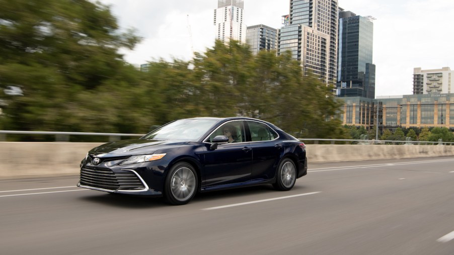 A Black Toyota Camry driving down a city street, the Toyota Camry is one of the best commuter cars