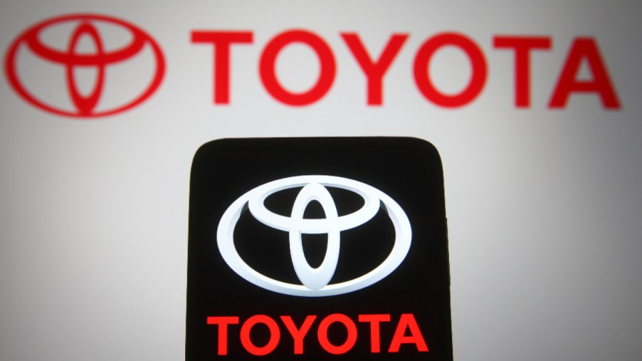 In this photo illustration, a Toyota logo seen displayed on a smartphone and a pc screen.