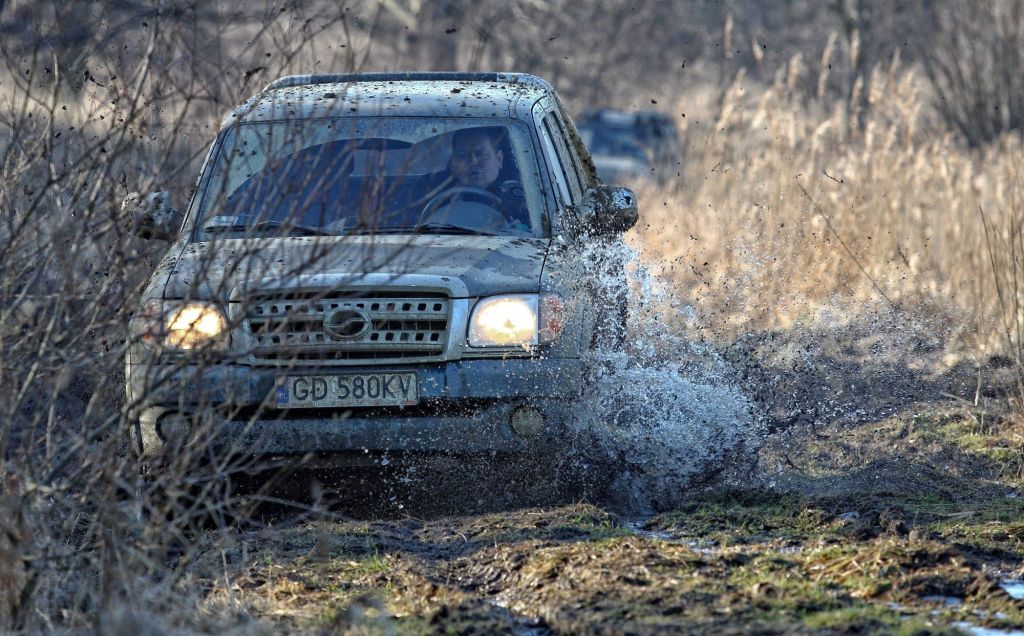 A pickup truck driving through mud during an off-road race