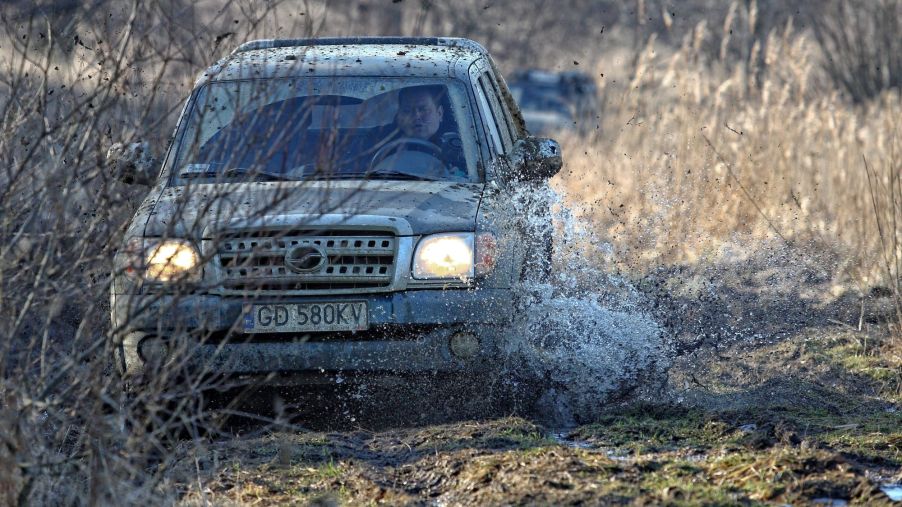 A pickup truck driving through mud during an off-road race