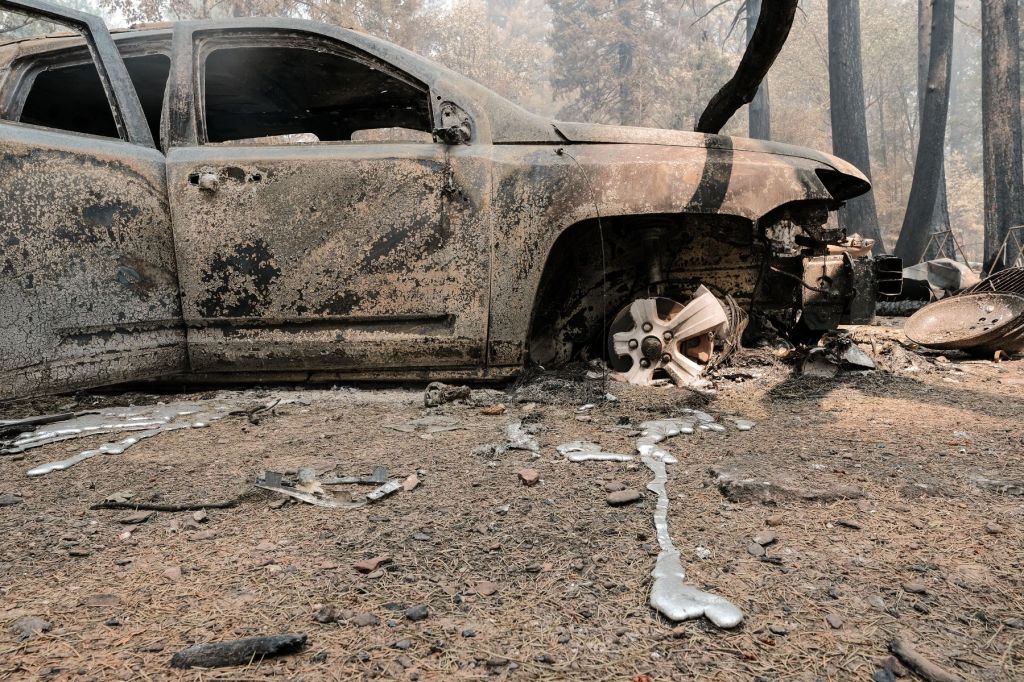 A burned vehicle and destroyed forest road from the Dixie Fire worsened by climate change
