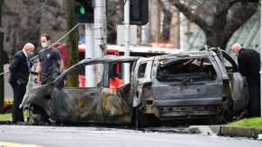 Detectives inspect the scene where a car crashed and burst into flames outside Melbourne's Royal Women's Hospital on August 20, 2021.