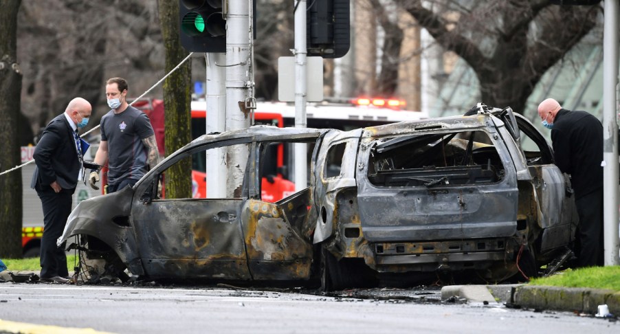 Detectives inspect the scene where a car crashed and burst into flames outside Melbourne's Royal Women's Hospital on August 20, 2021.