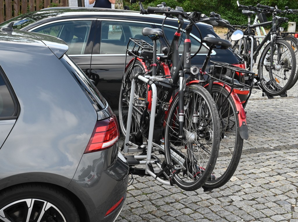 Two vehicles with rear bike racks are parked at a rest area