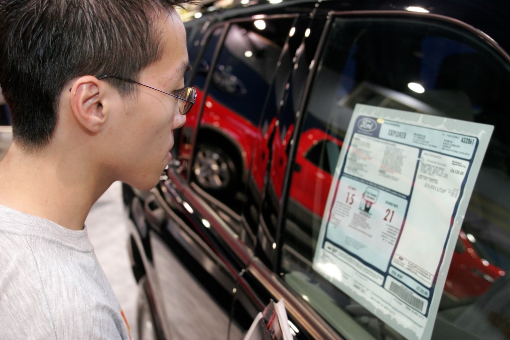 A person looks at a Ford Explorer price sticker, including the MSRP, at the 2005 International Auto Show
