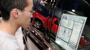 A person looks at a Ford Explorer price sticker, including the MSRP, at the 2005 International Auto Show
